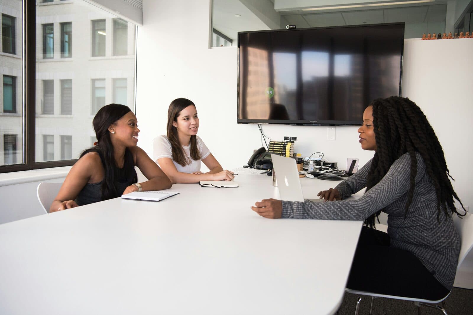 Three colleagues talking across a conference table in a bright office
